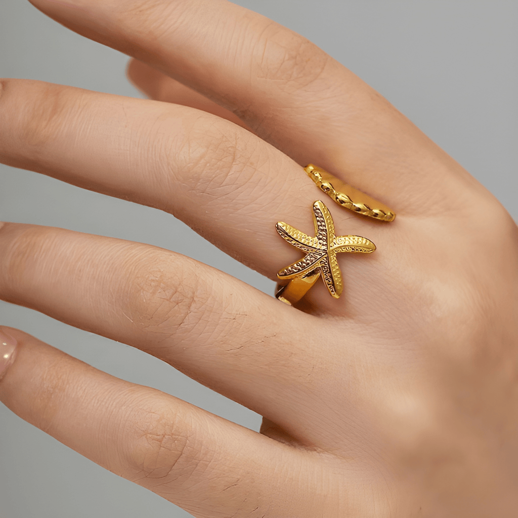 Gold seashell and starfish statement ring worn on woman's finger