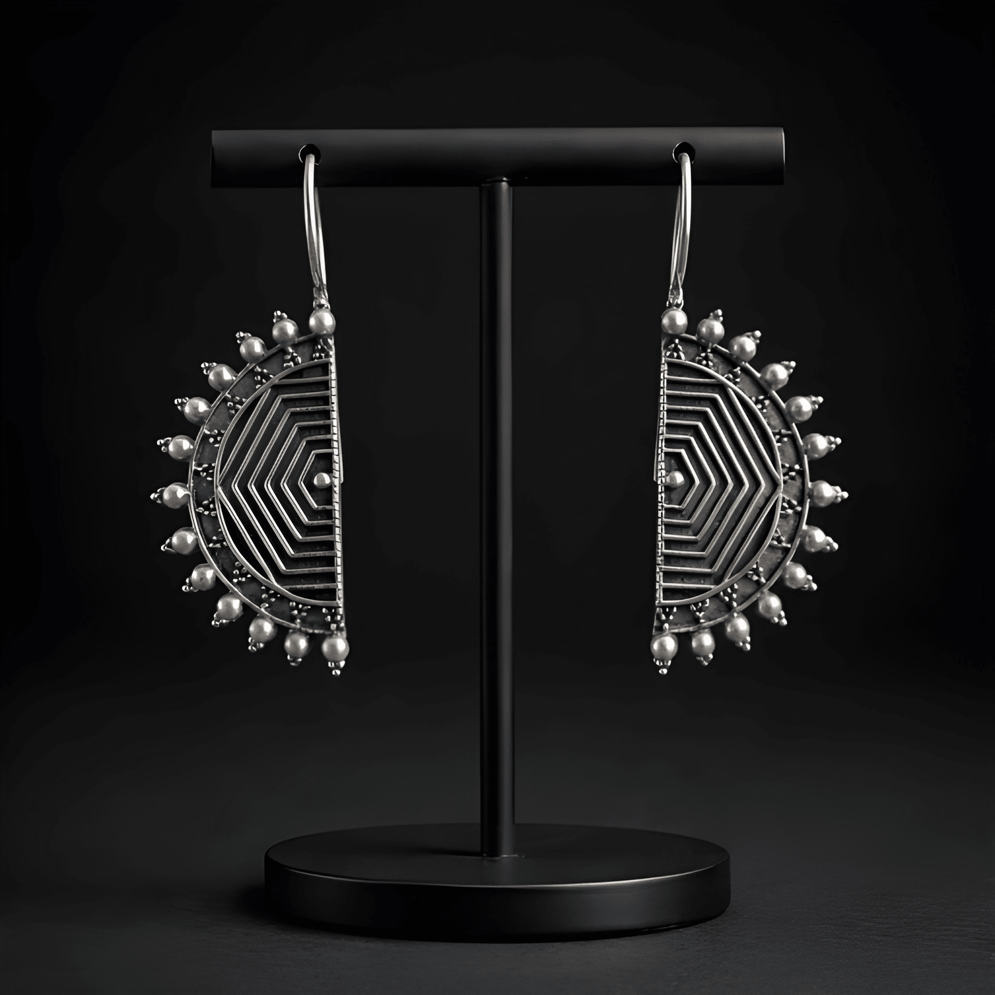 Oxidised half-moon maze earrings displayed on black stand
