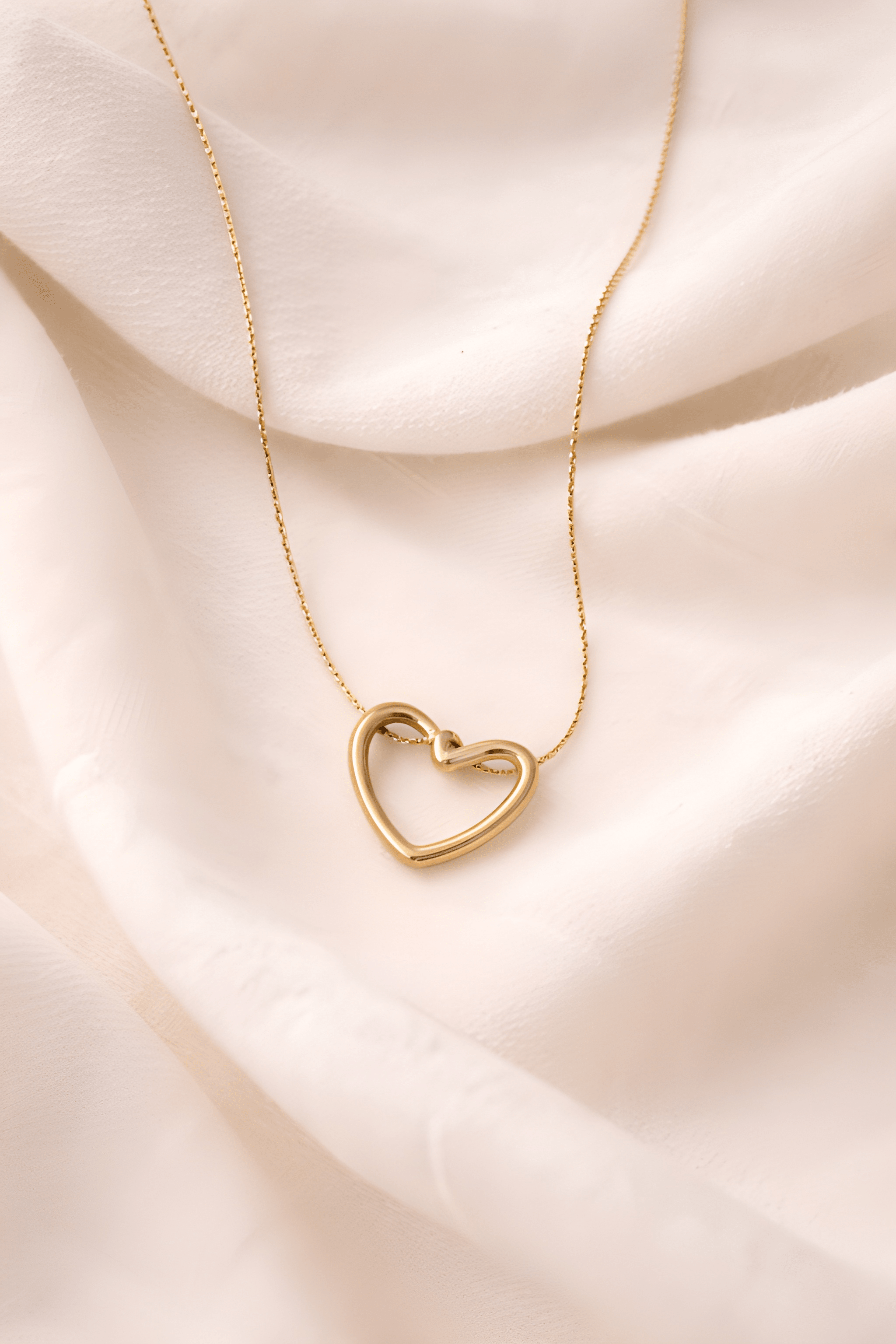 Minimal gold heart pendant necklace on soft neutral background