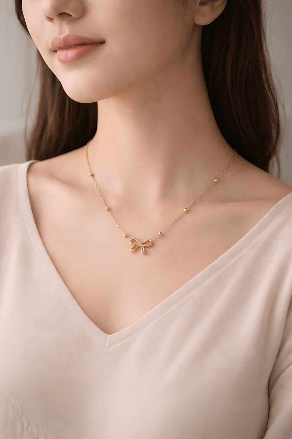 Woman wearing minimal gold bow necklace with bead chain