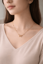 Woman wearing minimal gold bow necklace with bead chain