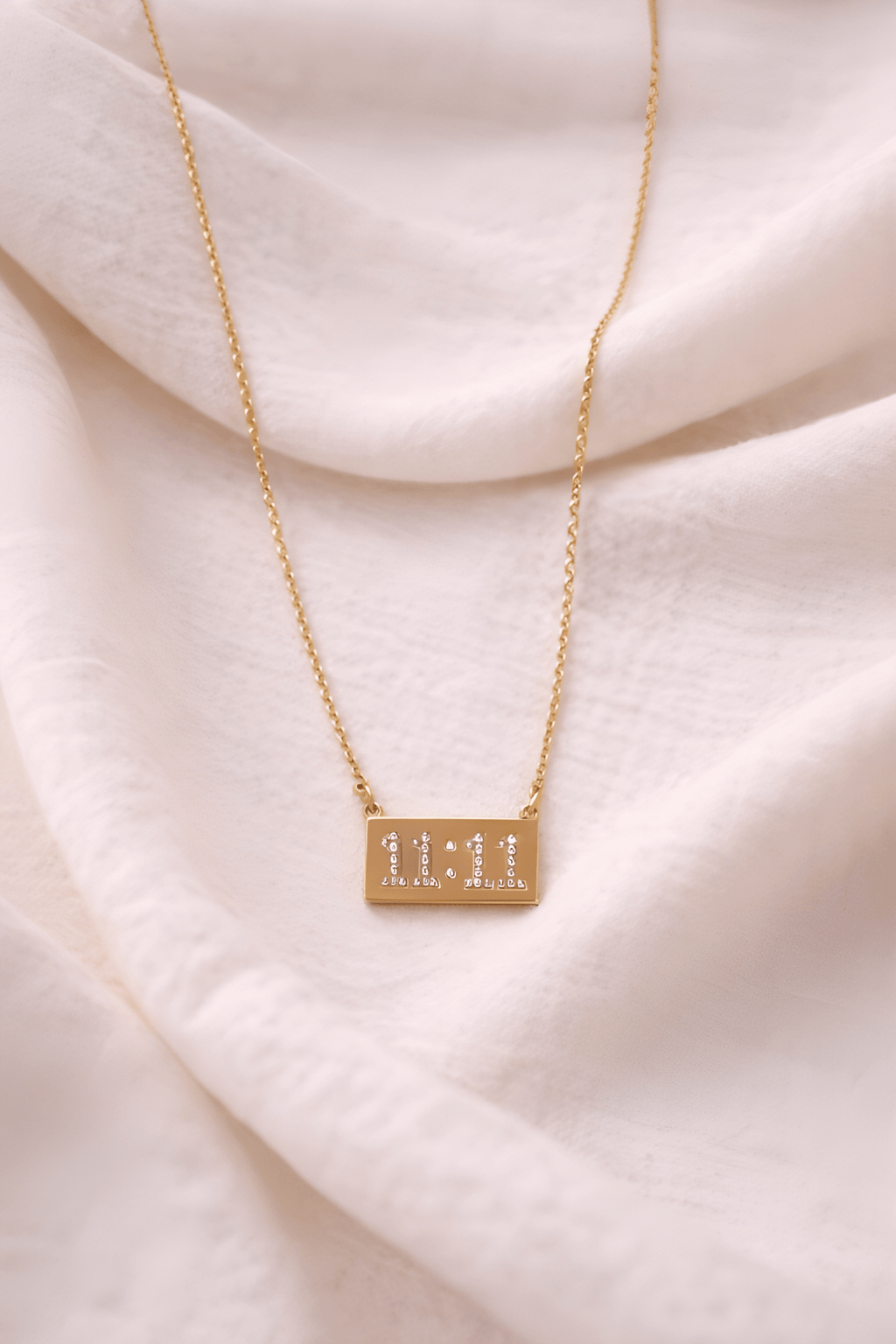 Gold 11:11 rectangular bar pendant necklace on neutral background