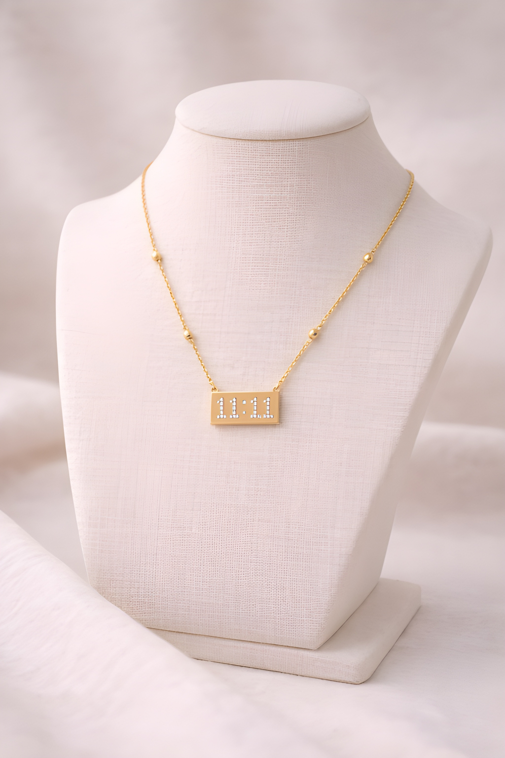 Gold 11:11 crystal bar necklace displayed on ivory stand