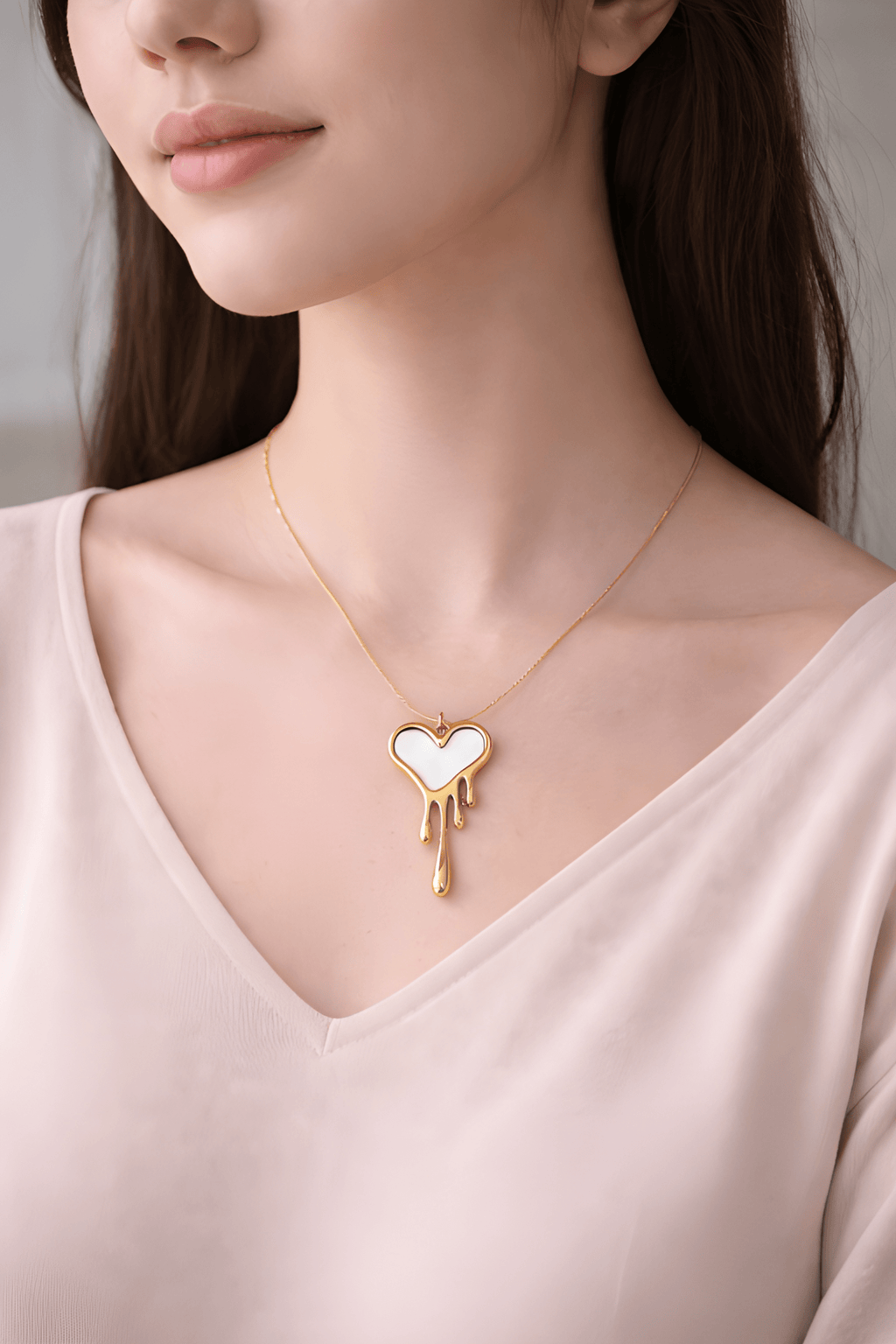 Woman wearing gold dripping heart necklace with white enamel detail