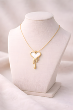 Dripping heart gold pendant necklace displayed on ivory bust stand
