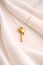 Gold melting heart pendant necklace on soft ivory fabric