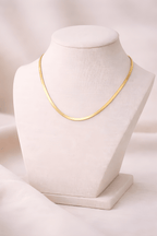 Gold flat snake chain necklace displayed on ivory bust stand