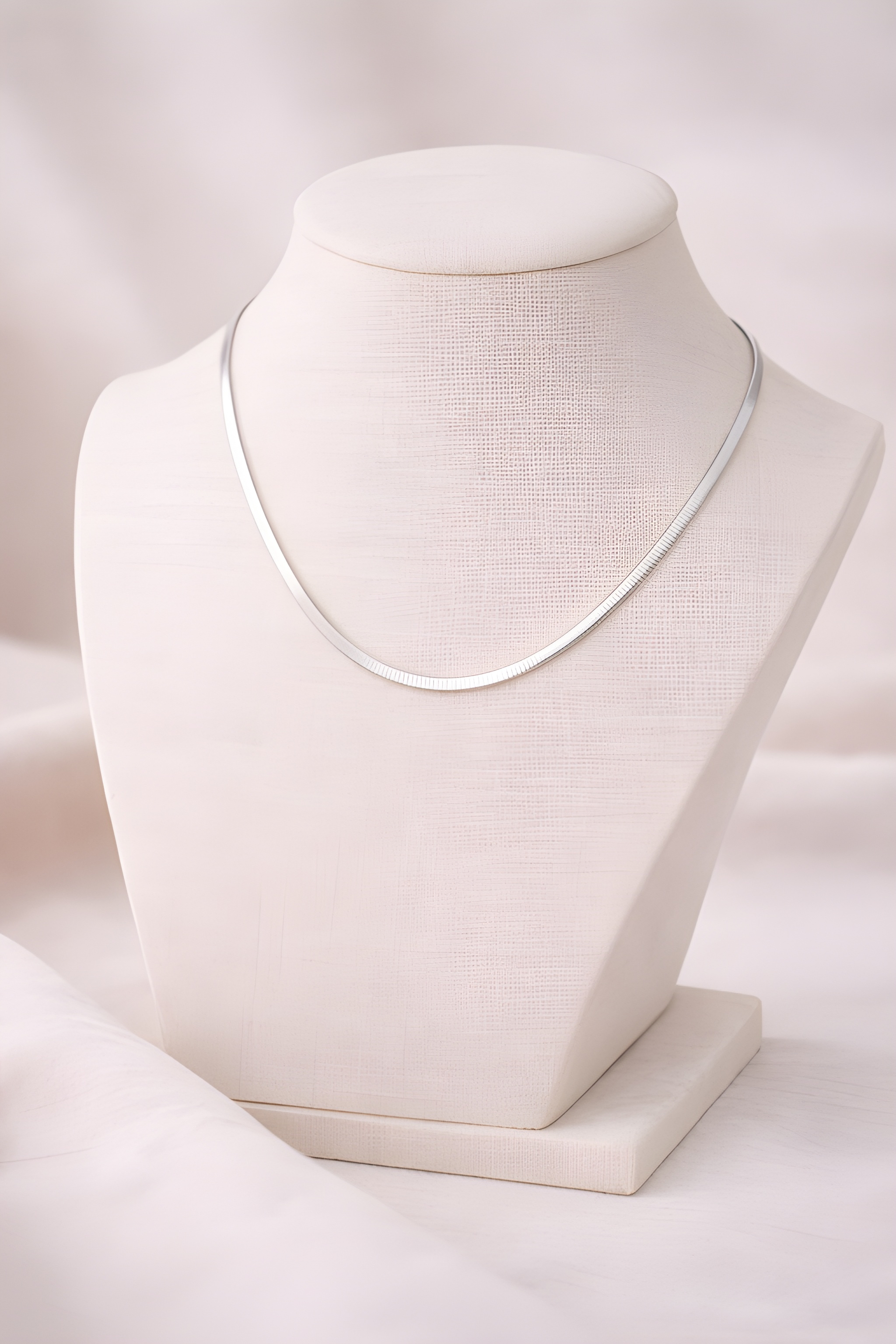 Silver flat snake chain necklace displayed on ivory bust stand