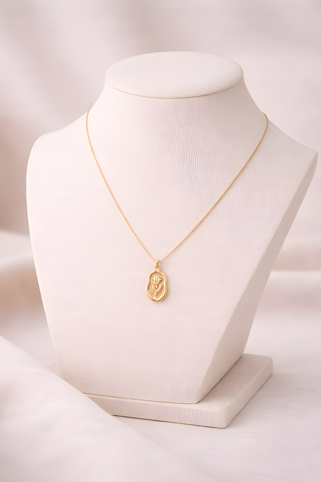 Gold rose engraved pendant necklace displayed on ivory bust stand