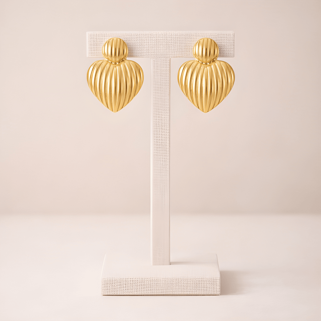 Ribbed gold heart stud earrings on ivory stand