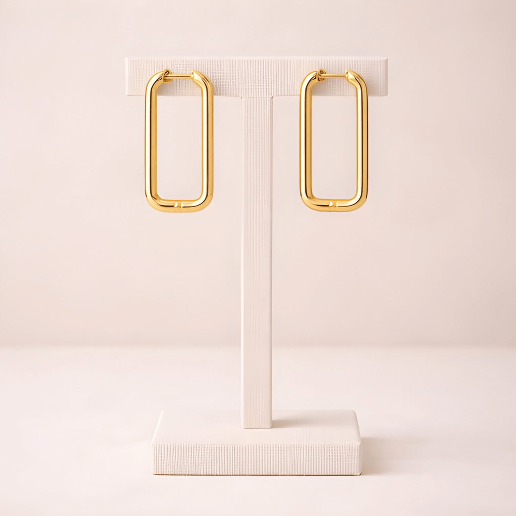 Rectangular gold hoop earrings on ivory stand