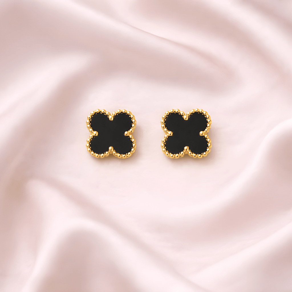 Black clover stud earrings with gold beaded frame on soft ivory background