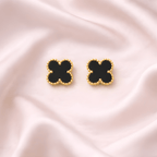 Black clover stud earrings with gold beaded frame on soft ivory background