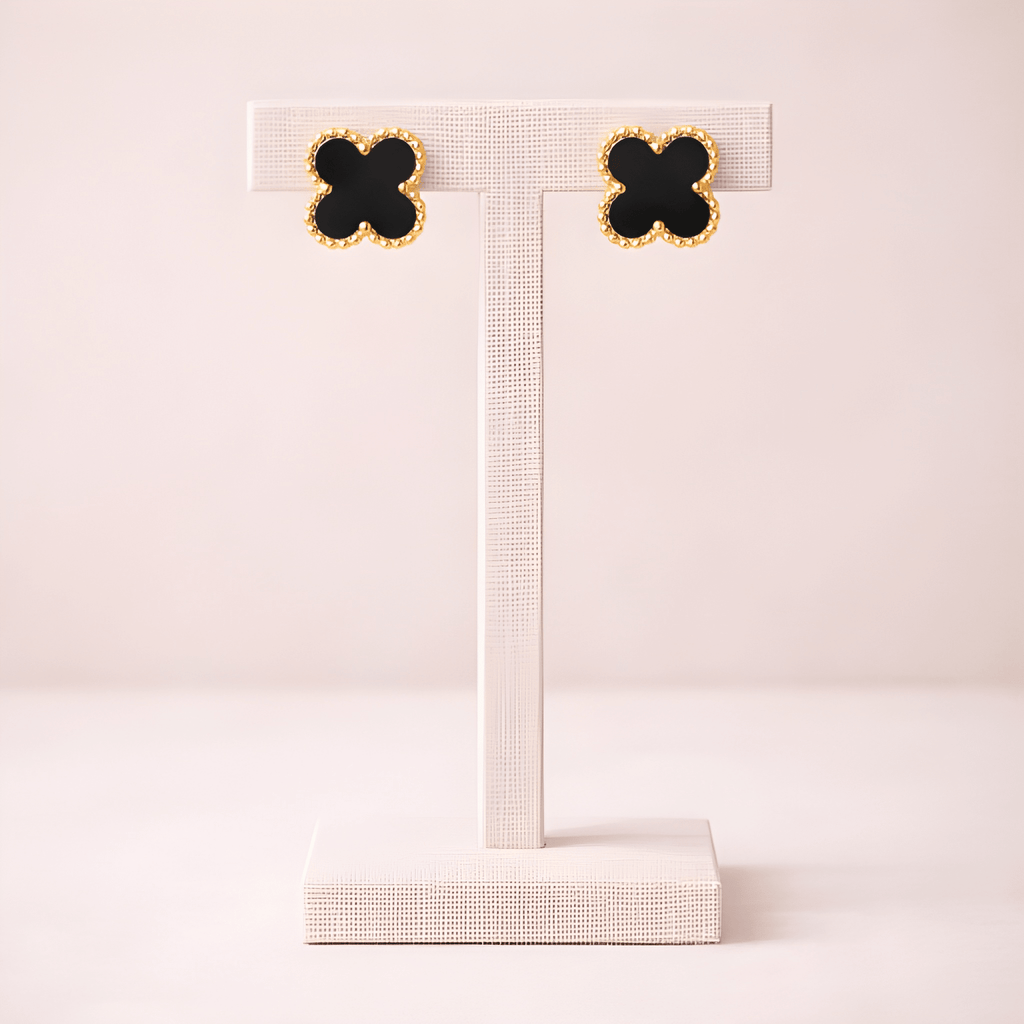 Black clover stud earrings displayed on ivory stand