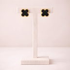 Black clover stud earrings displayed on ivory stand