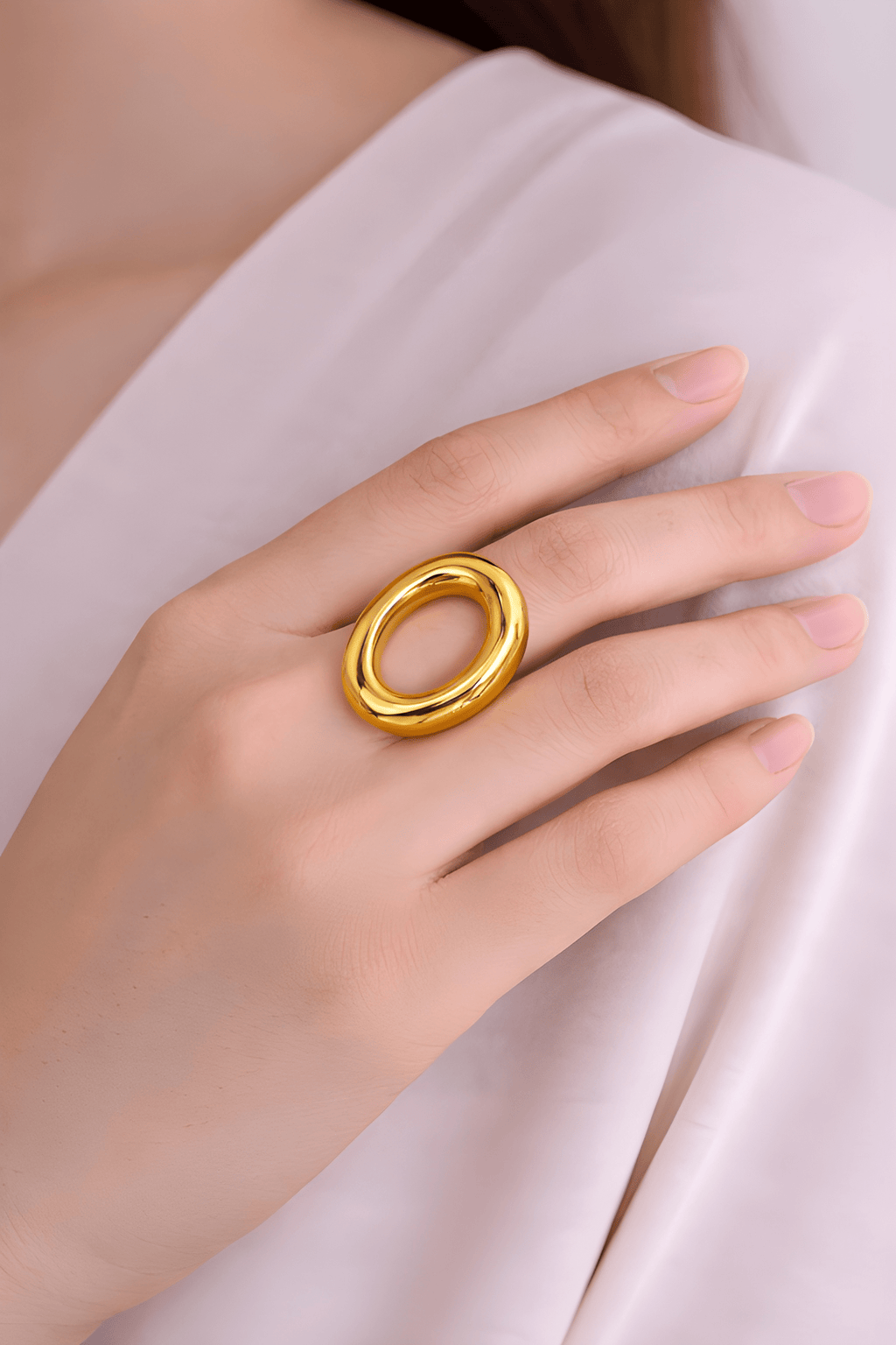 Bold oval gold statement ring worn on woman's finger