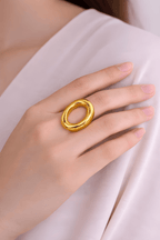 Bold oval gold statement ring worn on woman's finger
