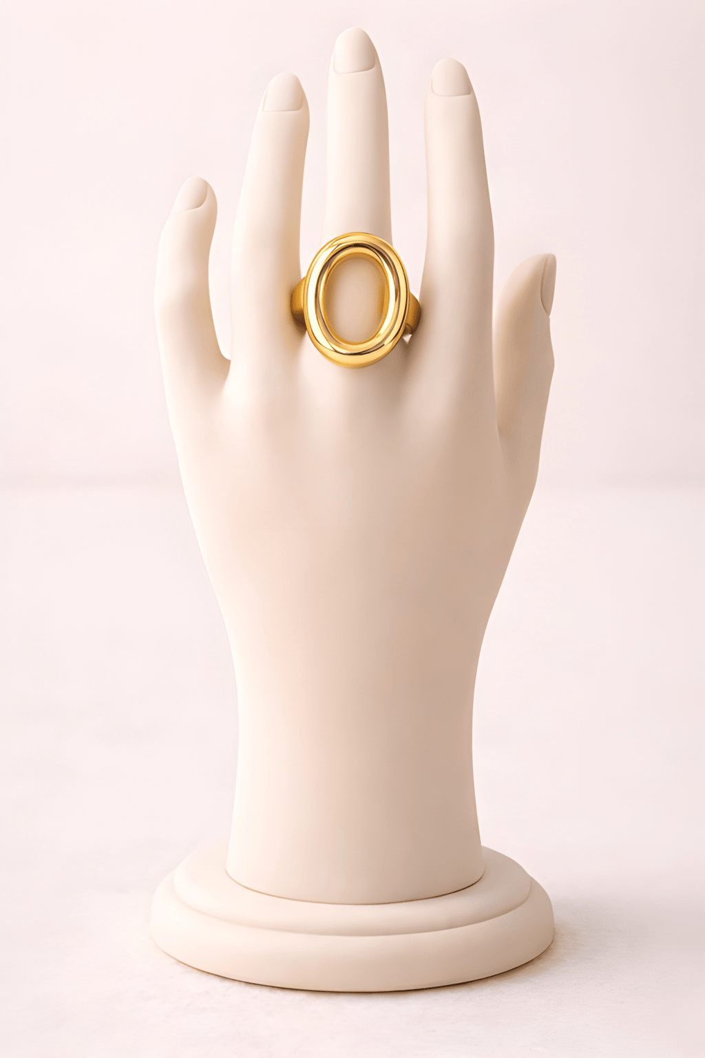 Sculpted oval gold ring displayed on ivory mannequin hand