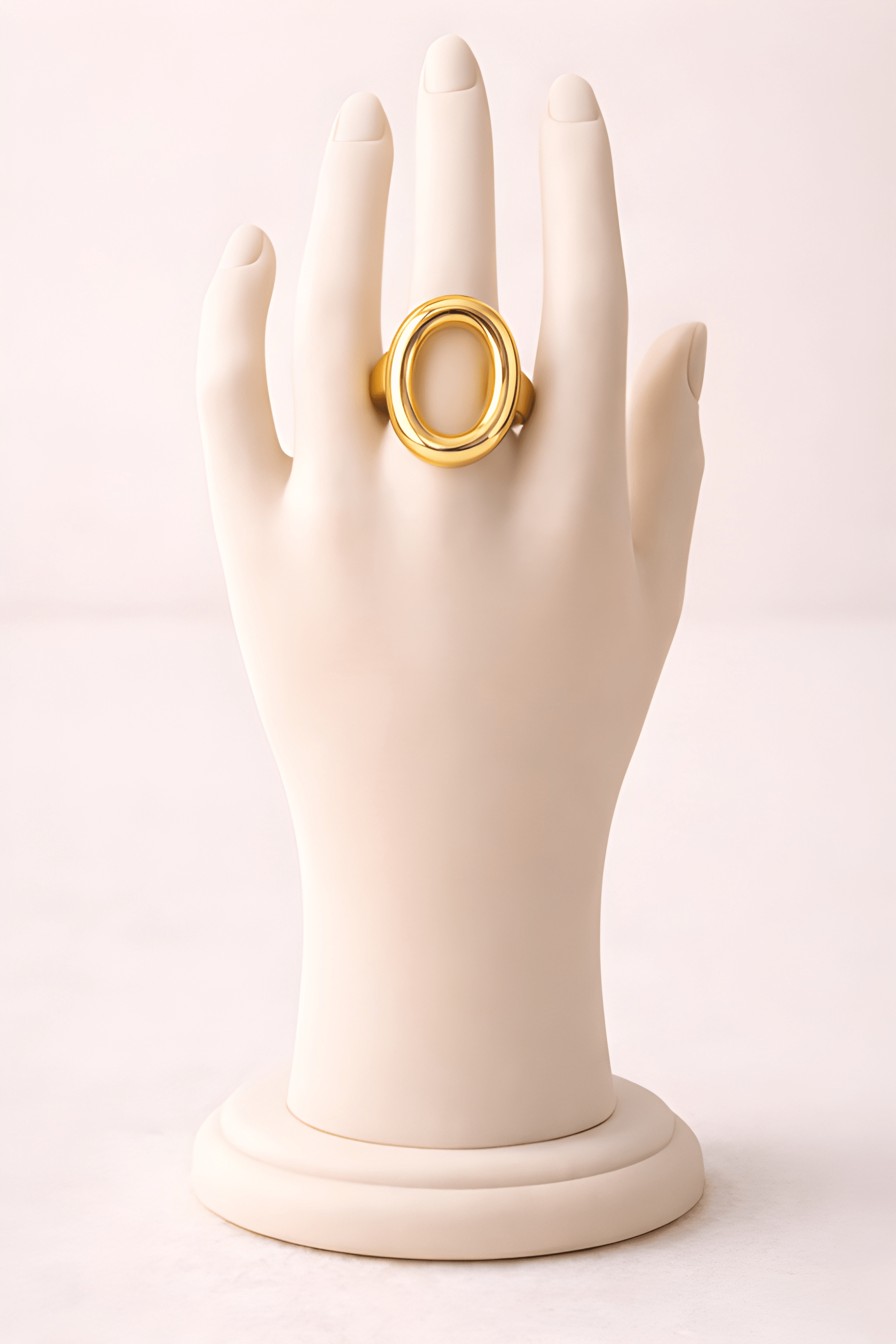 Sculpted oval gold ring displayed on ivory mannequin hand