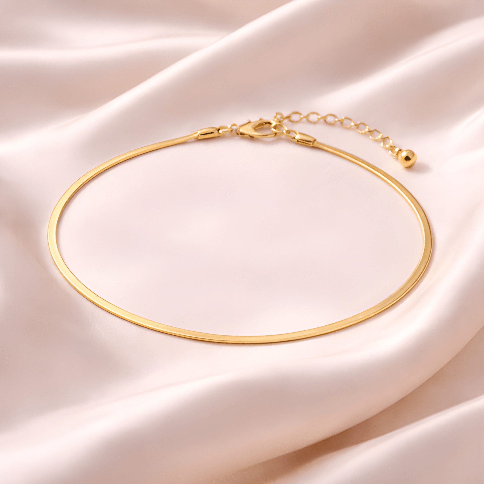 Minimal gold snake chain anklet on blush satin fabric