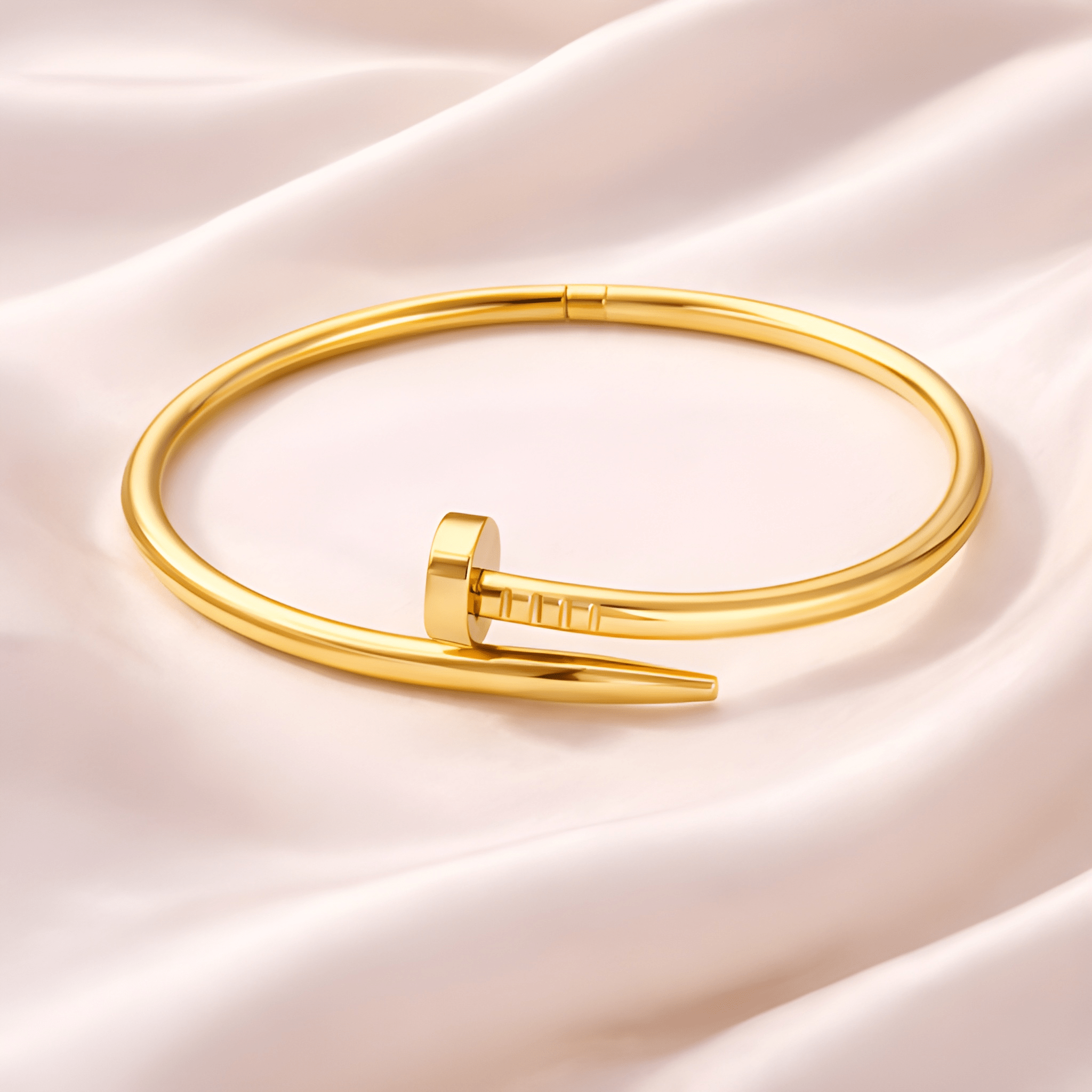 Minimal gold nail bangle bracelet on blush satin