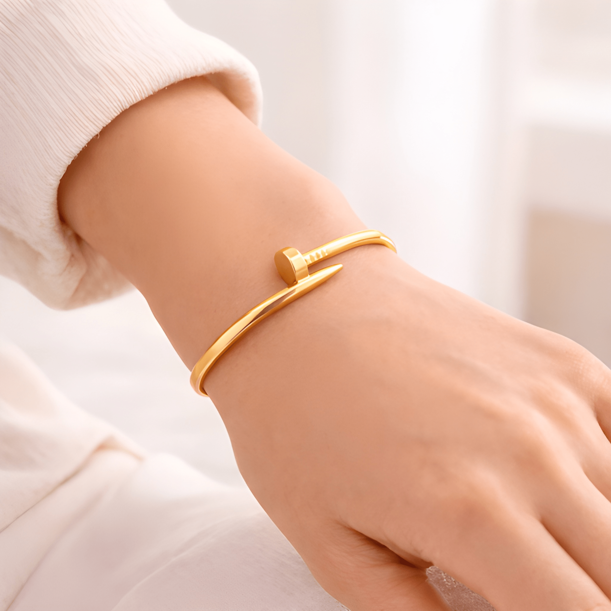 Gold nail bangle bracelet worn on woman's wrist