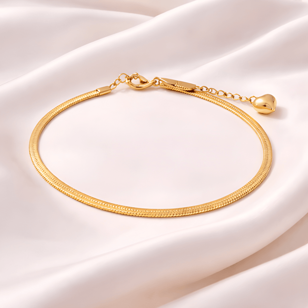 Gold snake chain bracelet with heart charm on blush satin