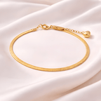Gold snake chain bracelet with heart charm on blush satin