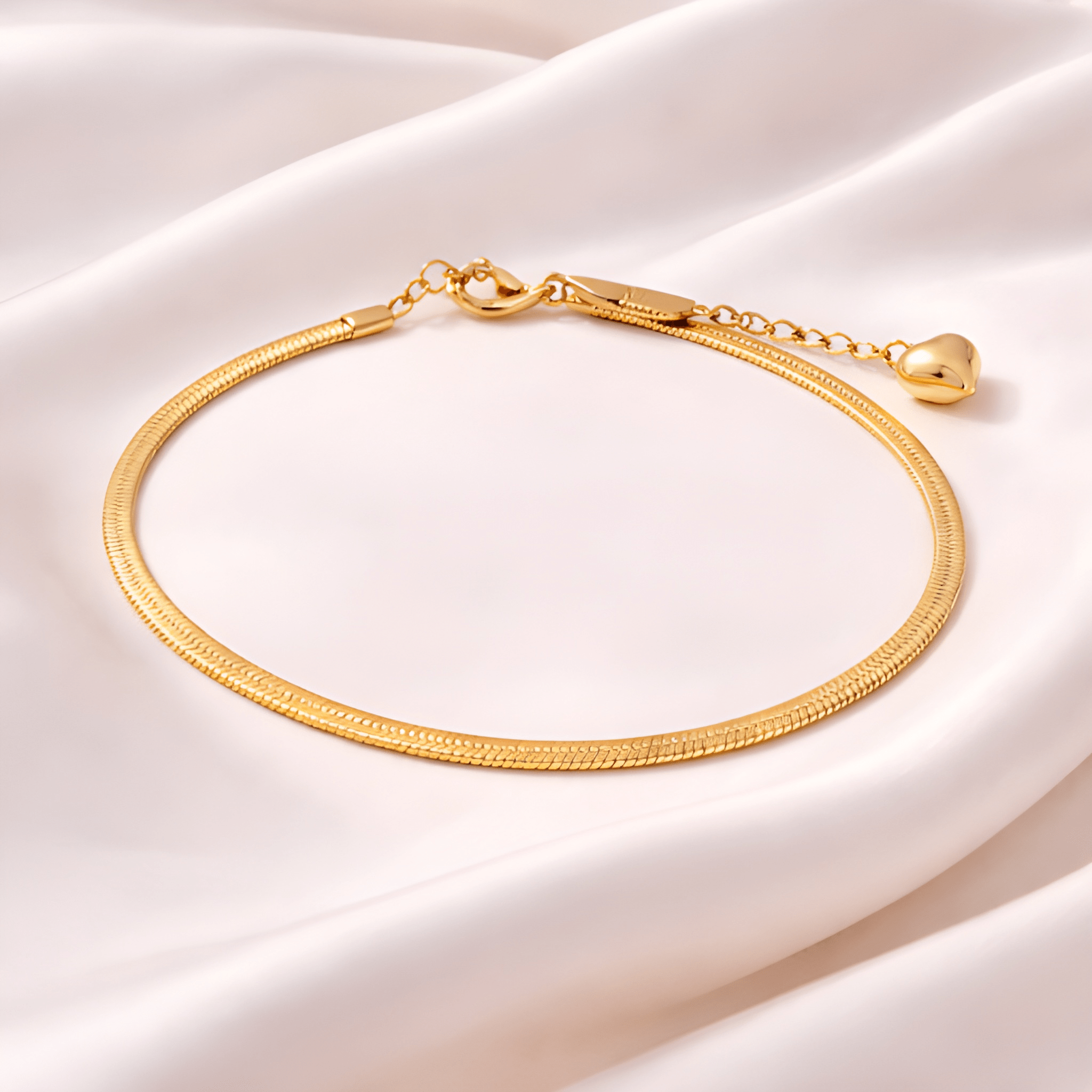 Gold snake chain bracelet with heart charm on blush satin