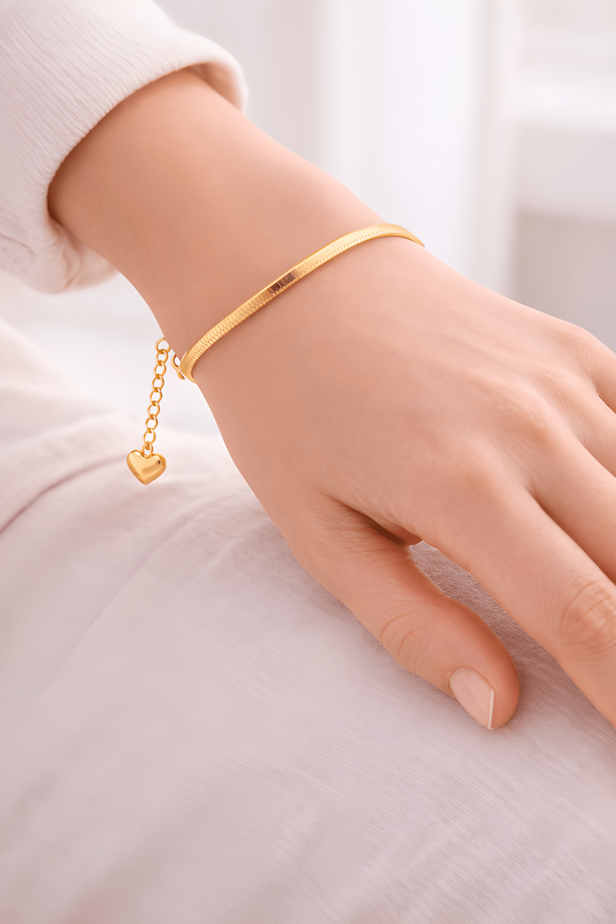 Minimal gold snake chain bracelet with heart charm worn on wrist