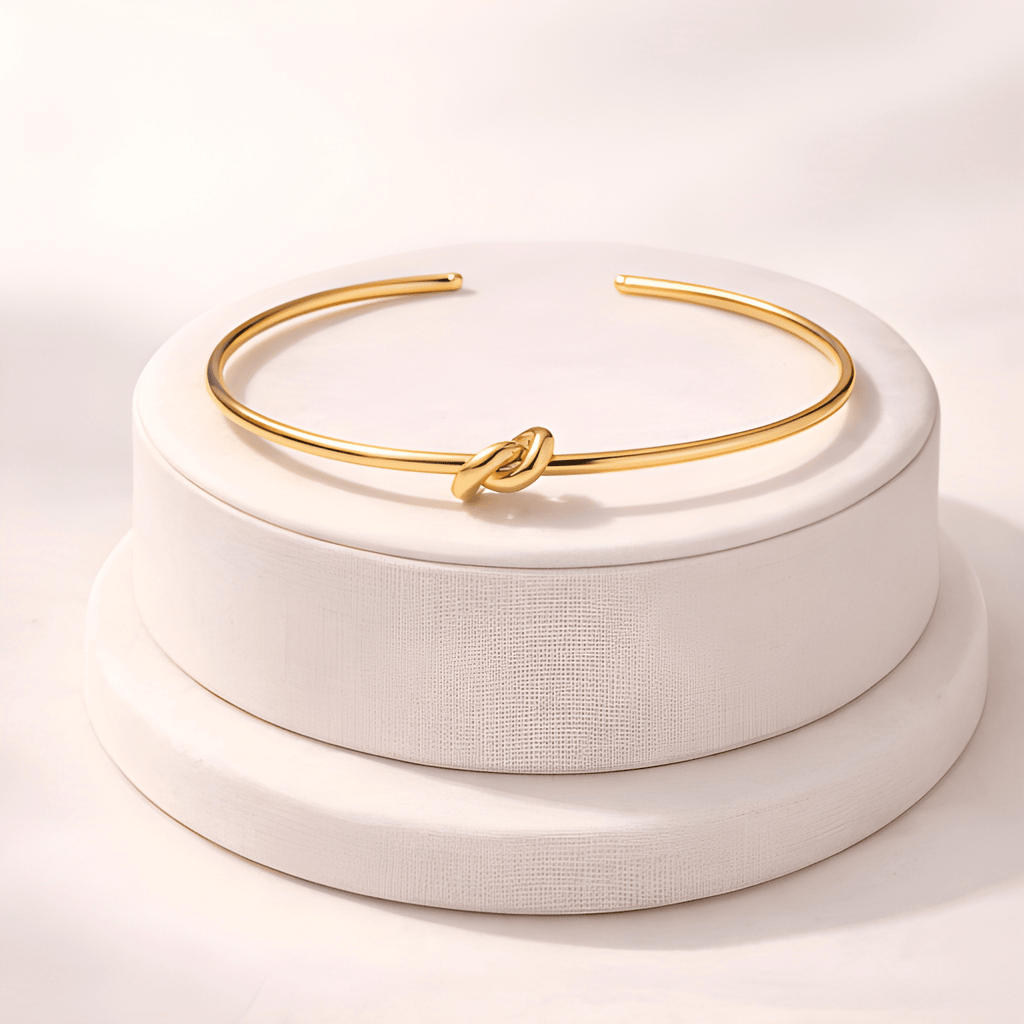 Gold knot cuff bracelet displayed on minimal ivory jewellery stand | Kayahh Jewels