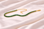 Emerald green tennis bracelet with gold setting on ivory silk background | Kayahh Jewels