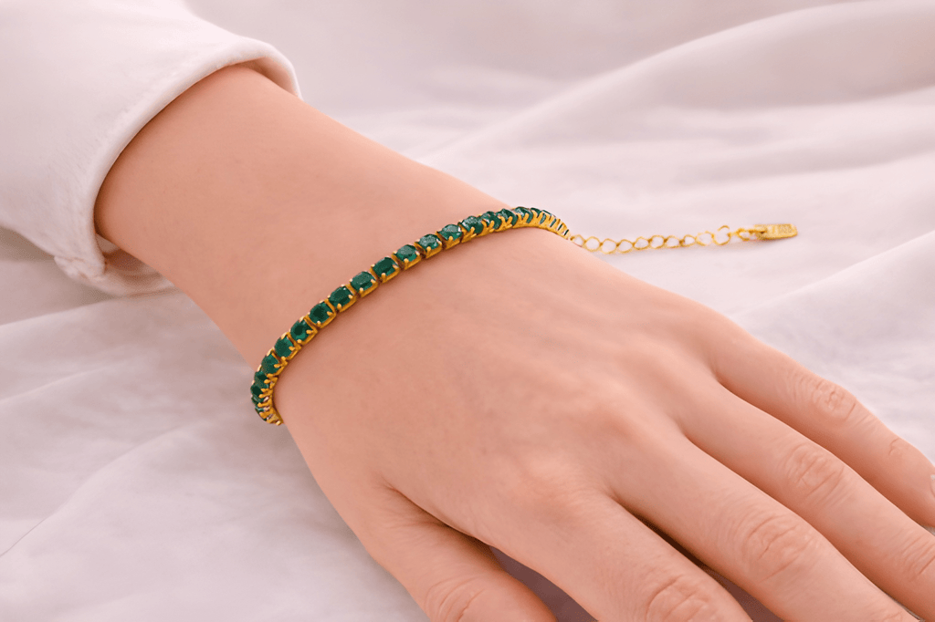 Woman wearing emerald green tennis bracelet with gold setting | Kayahh Jewels