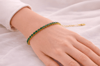 Woman wearing emerald green tennis bracelet with gold setting | Kayahh Jewels