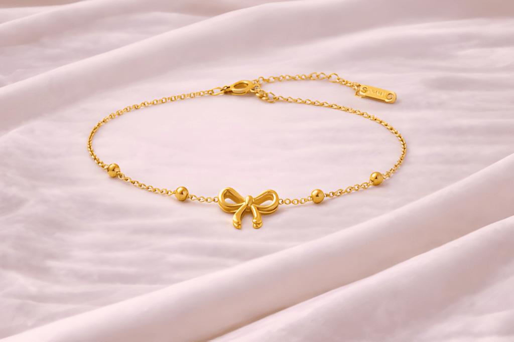 Gold bow chain bracelet with bead accents on soft ivory fabric background | Kayahh Jewels