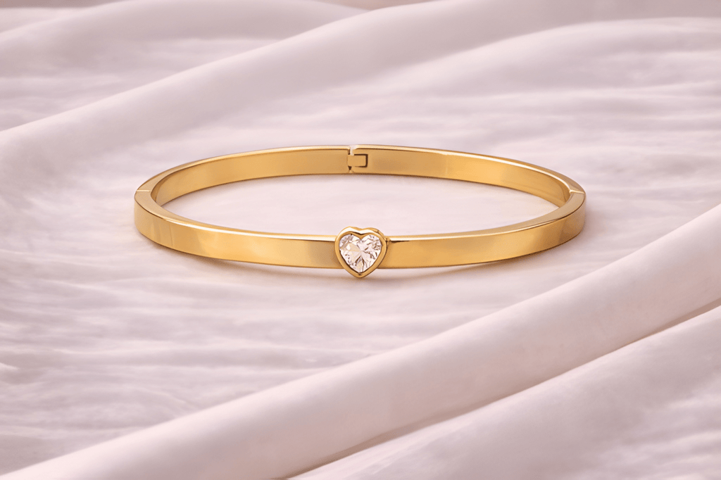 Gold crystal heart bangle bracelet on soft ivory fabric background | Kayahh Jewels