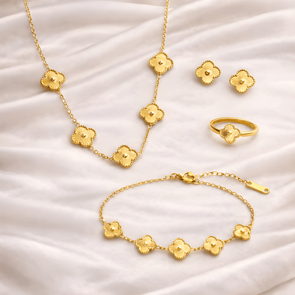 Gold floral clover jewellery set including necklace, bracelet, ring and earrings on ivory silk background | Kayahh Jewels