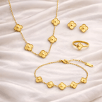 Gold floral clover jewellery set including necklace, bracelet, ring and earrings on ivory silk background | Kayahh Jewels