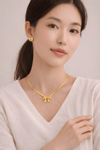 Woman wearing gold bow pendant necklace with matching bow stud earrings | Kayahh Jewels
