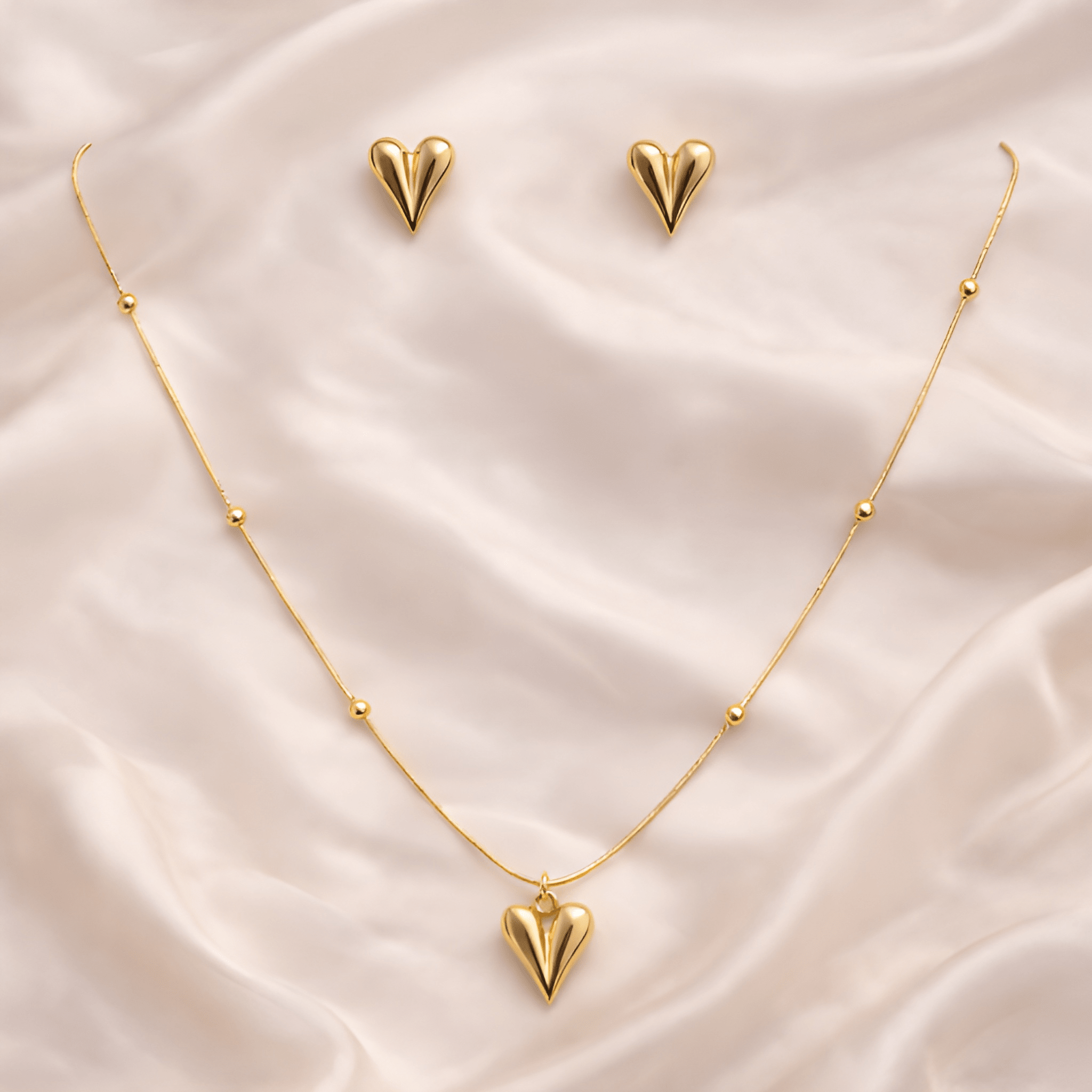 Gold pointed heart pendant necklace with matching pointed heart stud earrings on ivory silk background | Kayahh Jewels