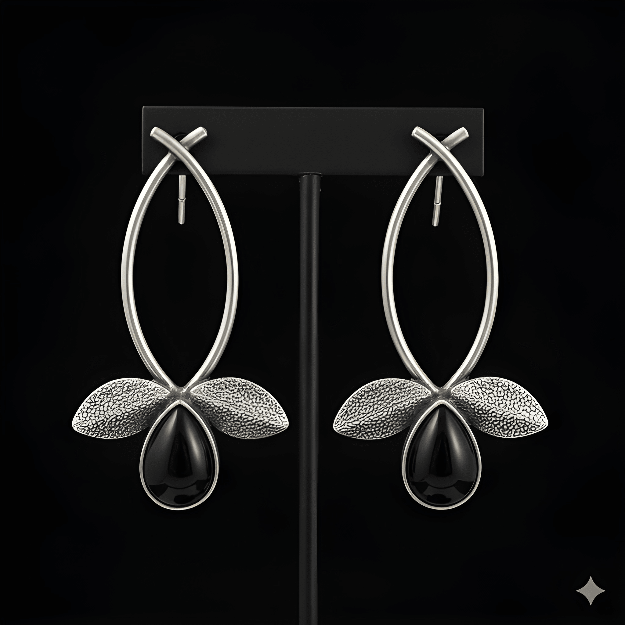 Silver leaf drop earrings displayed on black stand
