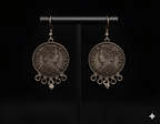 Antique finish coin drop earrings displayed on black stand

