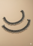 Handcrafted spacing karigari oxidised silver anklet with openwork detailing on golden background

