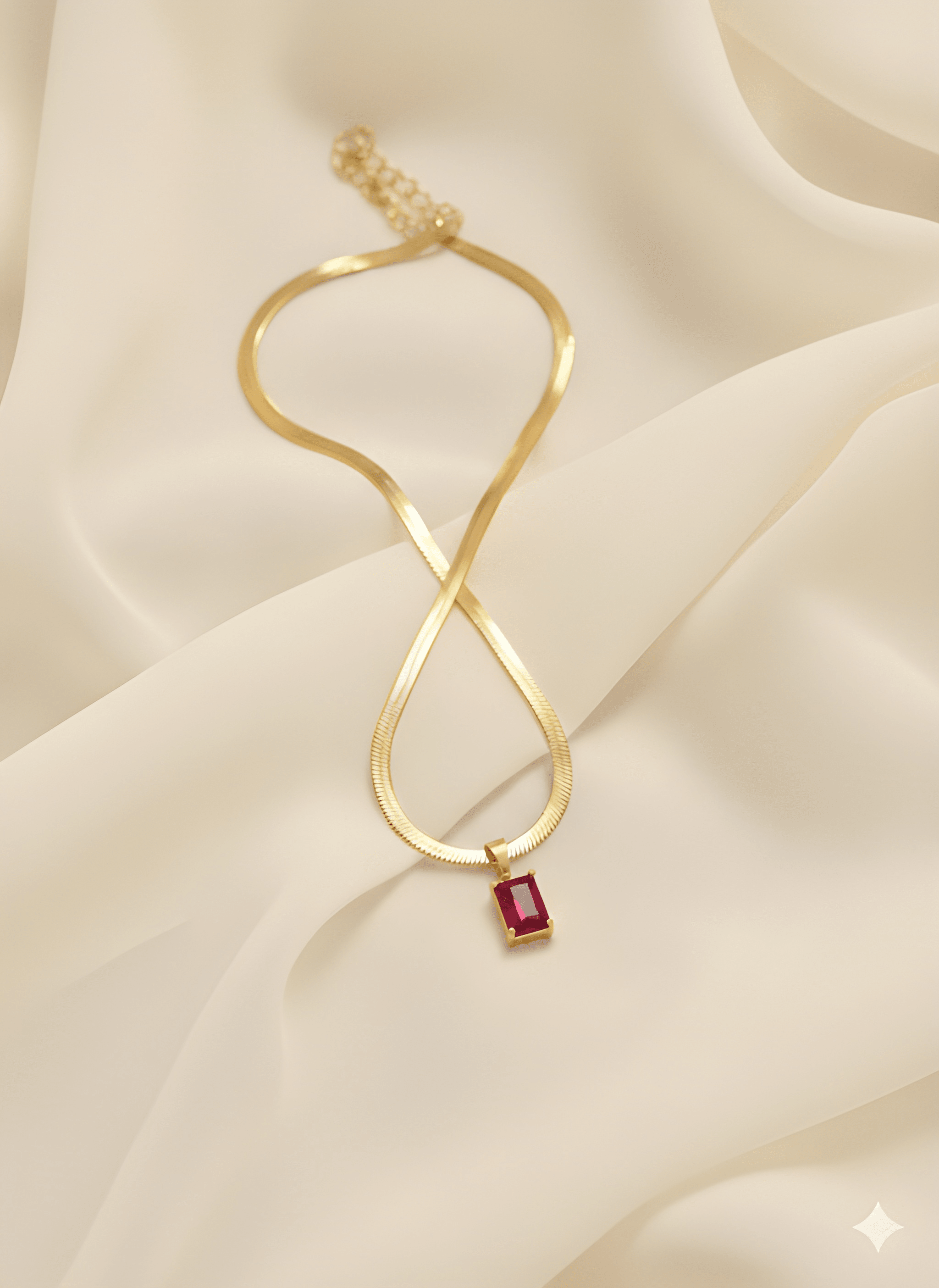 Gold rectangle pendant necklace with ruby red stone on ivory fabric