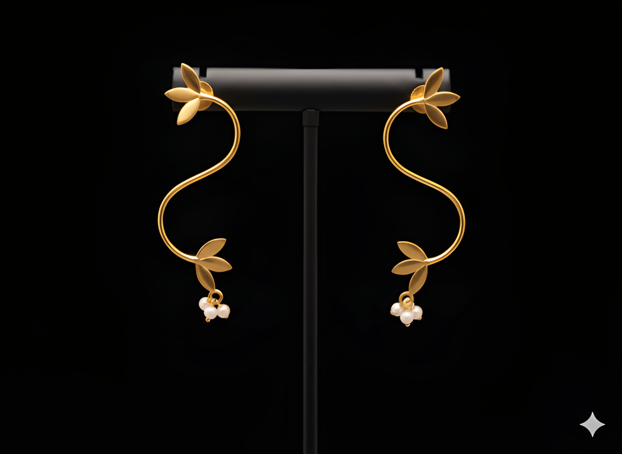 Gold S-shaped vine curve earrings displayed on black stand
