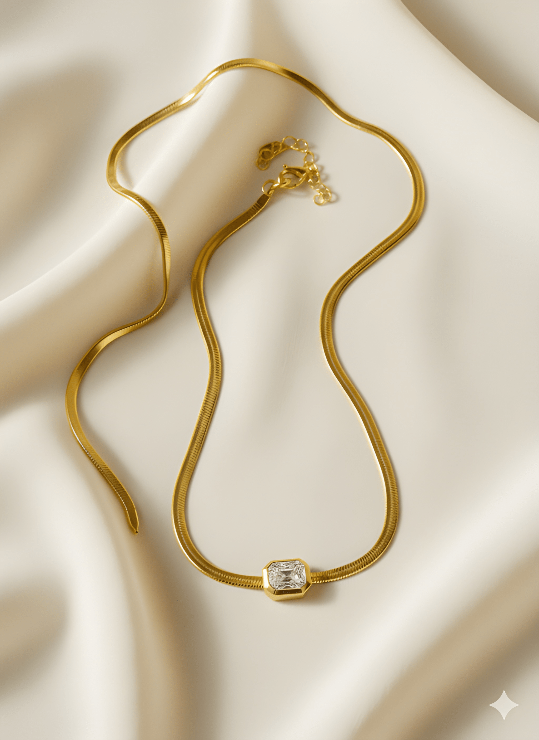 Gold rectangle pendant necklace with white stone on ivory fabric