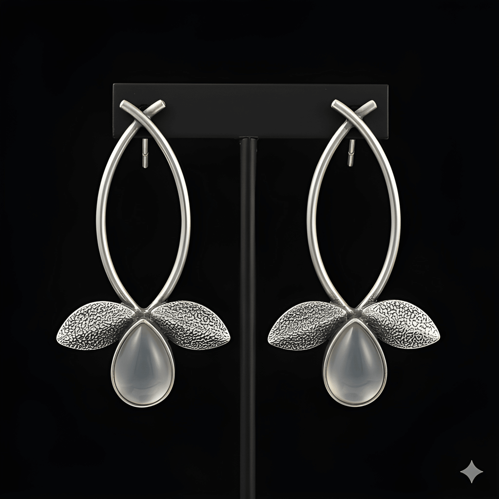 Silver leaf drop earrings displayed on black stand
