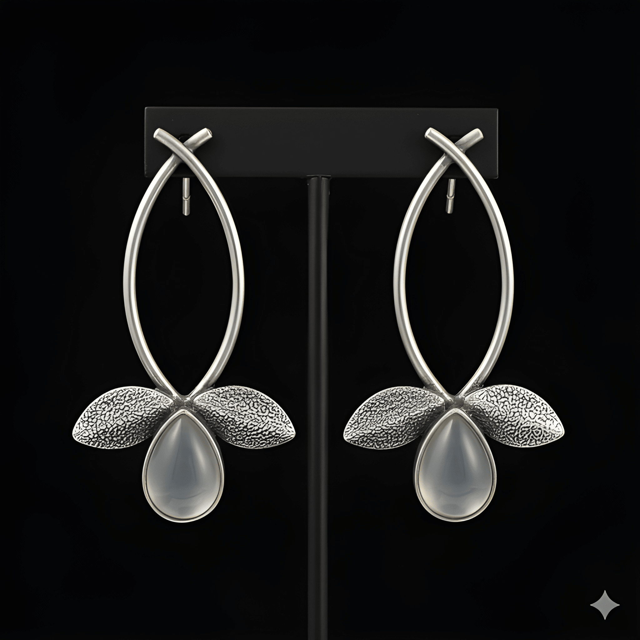 Silver leaf drop earrings displayed on black stand
