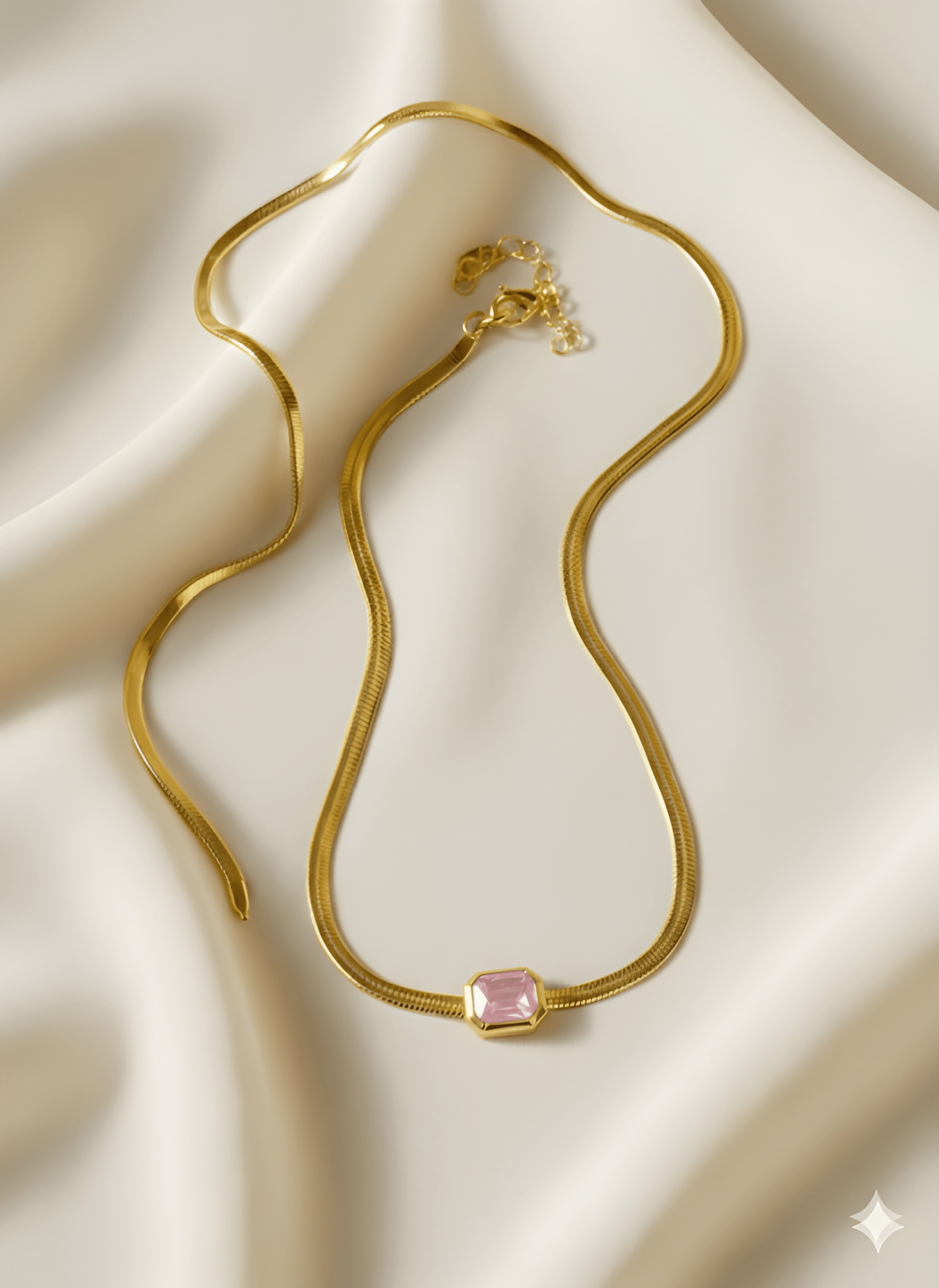 Gold rectangle pendant necklace with blush pink stone on ivory fabric
