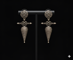 Shell inspired tribal drop earrings displayed on black stand
